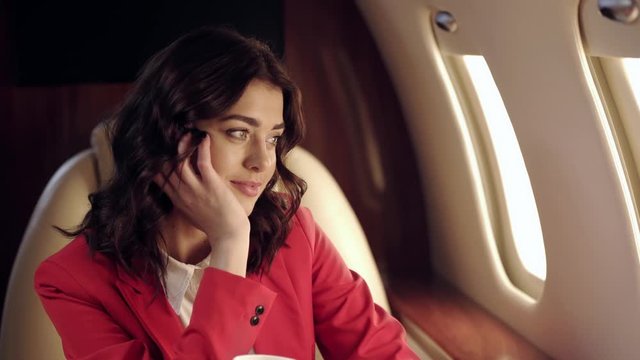 dreamy businesswoman looking in illuminator while traveling by plane