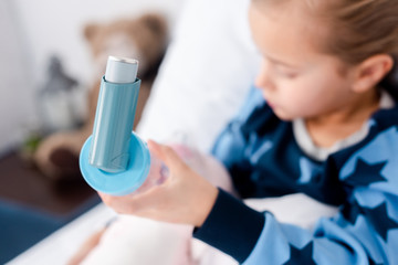 selective focus of sick child holding inhaler with spacer in bedroom - obrazy, fototapety, plakaty