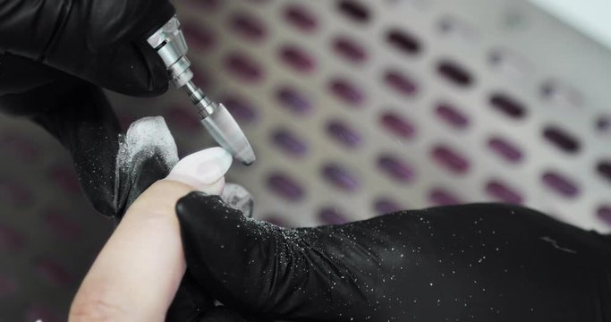 Manicure master removing old shellac from woman's nail using electric machine. Making manicure for woman using electric nail file drill machine, hands closeup view. Hardware manicure in beauty salon.