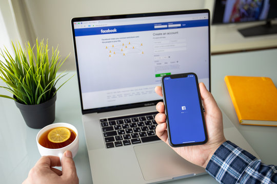 Man hand iPhone 11 above Macbook Pro 16 social Facebook