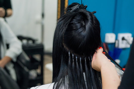 Professional woman applying hair extensions with different types of grips. Nano rings extensions made from real humas hair.