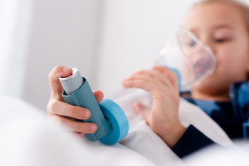 selective focus of diseased kid using inhaler with spacer - obrazy, fototapety, plakaty