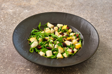 Arugula Salad with Pear on a black plate