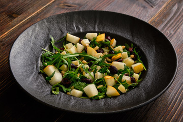 Arugula Salad with Pear on a black plate