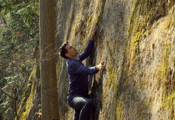 View of a young man climbing on a rock wall in the forest