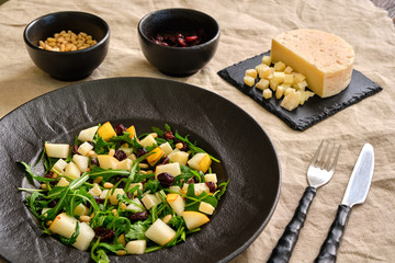 Arugula Salad with Pear on a black plate with ingredients