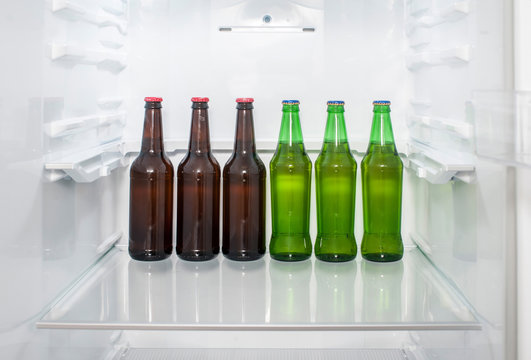 Green And Brown Glass Beer Bottles Stand On A Shelf In The Refrigerator