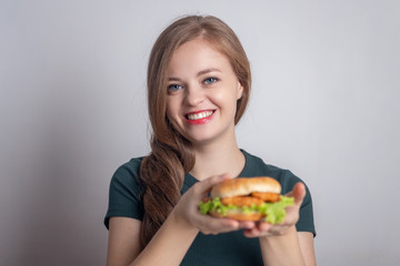 Smiling young Caucasian woman girl holding eating chicken burger