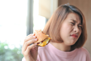 Unpalatable food makes not enjoy eating ,A girl was fulled after eating burger,Burger is hight calories food,Selective focus