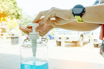Woman uses her hand to press hand sanitizer bottle to clean her hand at wayside in the city. Concepts of Flu virus, Covid-19 (Coronavirus disease). Selective focus on alcohol gel bottle.