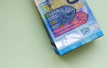 A bundle of Euro banknotes and coins on a light background