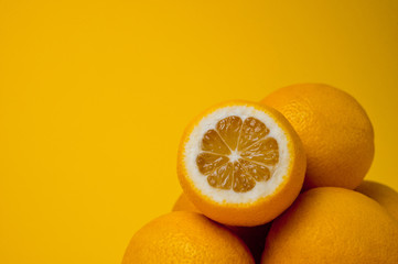 Ripe and juicy lemons shot on a yellow background. Background for vitamins and fruits.