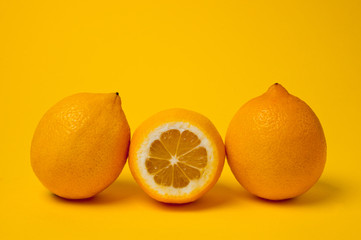 Ripe and juicy lemons shot on a yellow background. Background for vitamins and fruits.