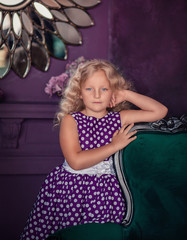 Cute girl in a purple dress with white polka dots in a purple room