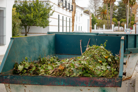 Metal skip filled with green waste on the road in Llerena Spain