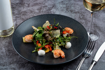 Prawns and mozzarella salad with lettuce on grey stone table