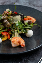Prawns and mozzarella salad with lettuce on grey stone table