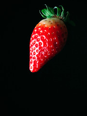 strawberry ripe juicy red berry falling flying on a black background