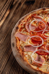 Close up of classic italian pizza with ham, onion rings and tomato, vertical, half of pizza