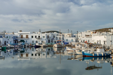 Panoramic view of Paros island popular tourist attraction, Naousa town. Promenade zone along port with restaurants and shops. Harbor of Aegean Sea, oats and yachts in quay at calm morning. Greece