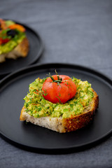 Toast avocado, tomato and shnit on a black dish