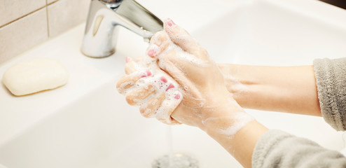 Female washing hands under the running water using natural soap