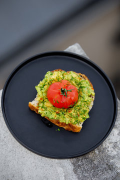 Toast avocado, tomato and shnit on a black dish