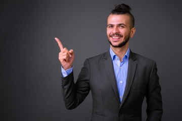 Portrait of happy bearded Turkish businessman in suit pointing up