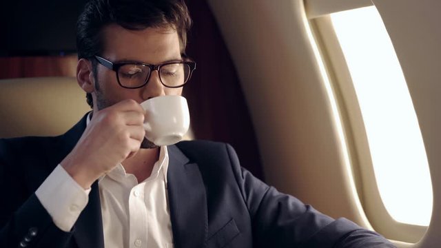 handsome businessman drinking coffee while traveling by plane