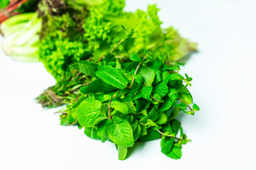 Obraz premium Bundles of salads on a white background isolated. Fresh greens: parsley, chard, dill, lettuce, mint, rosemary. detox concept, healthy energy boost with greens