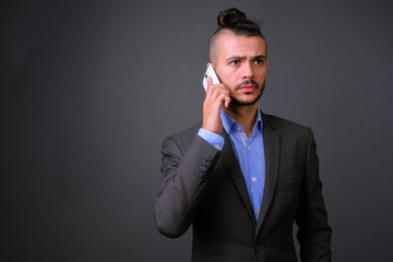 Portrait of bearded Turkish businessman in suit talking on the phone