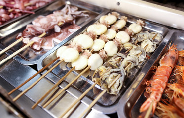 Squids on wooden sticks for grilling.