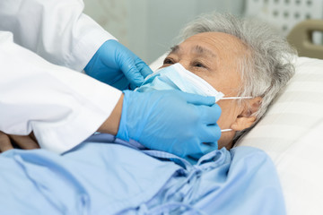 Doctor help Asian senior or elderly old lady woman patient wearing a face mask in hospital for protect safety infection and kill Novel Coronavirus (2019-nCoV) Covid-19 virus.