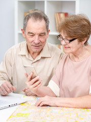 Senior couple planning holiday use smartphone and laptop