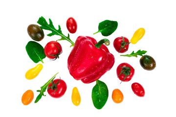 Fresh vegetables and herbs, arugula leaves, cherry tomatoes of different colors and basil around a bell red pepper isolated on white
