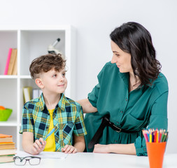 Mother and her little son doing homework together at home
