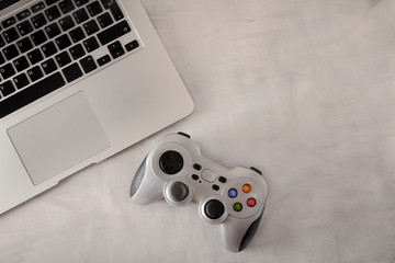 Wireless PC game controller on a grey background. Game console with a laptop. The concept of video...