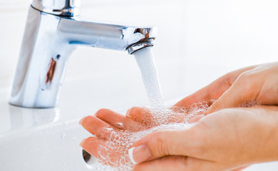Hygiene concept. Woman washing hands under the faucet with pure clear water.