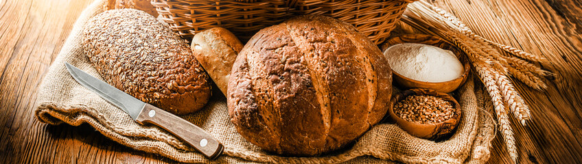 Various bread with wheat on old table. Bakery food concept panorama or wide banner baker's ware photo.