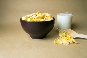 Cereal in a clay bowl, a wooden spoon with cereal and a glass of milk