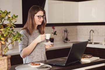 Young concentrated woman enjoying work on laptop. Positive female student doing homework, watching online webinar, listening audio course, writing emails, distantly working with wifi 