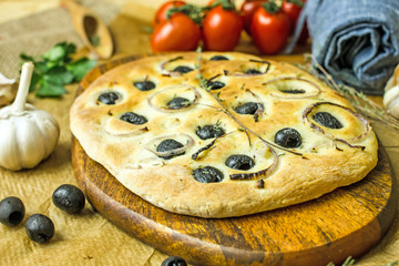 Traditional Italian focaccia with olives, spices, garlic on a wooden table. Homemade bread with olives. Copy space, top view