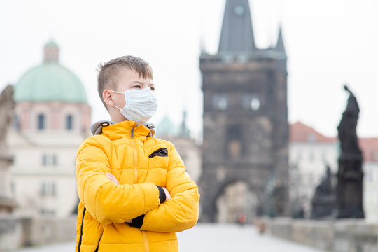 Portrait Of A Boy Wearing Medical Mask On Charles Bridge In Prague. Coronavirus Epidemic Concept