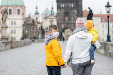 Family wearing a medical masks on Charles Bridge in Prague. Coronavirus epidemic concept