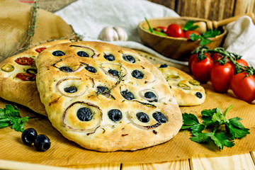 Traditional Italian focaccia with olives, spices, garlic on a wooden table. Homemade bread with olives. Copy space, top view