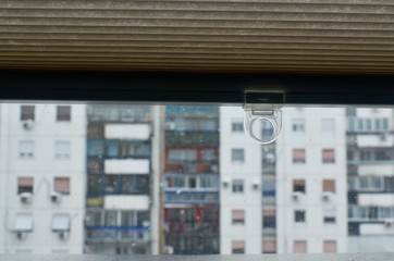 View through a window with a half raised blind to a next residential building during a snowy morning