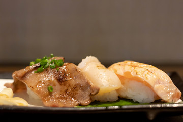 Different types of sushi on plate; grilled beef tongue (ox tongue), hotate and salmon sushi.