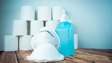 Many toilet paper rolls at home of hoarder with medical surgical masks and sanitizer hoarding amidst panic buying for corona virus outbreak shortage. Last stock of essential products for pandemic