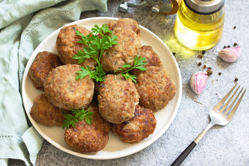 Homemade juicy delicious meat cutlets in plate, meatballs from minced meat on a gray stone table.
