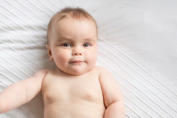 Cute happy 7 month baby girl lying on bed